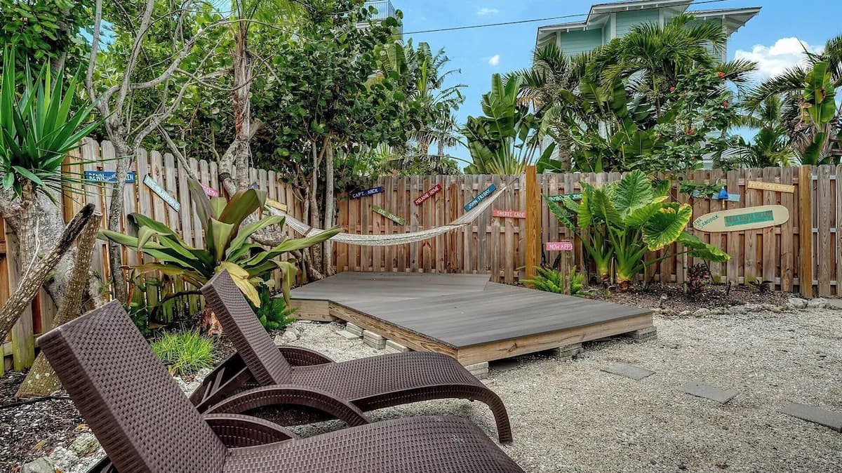 Loungers facing the low deck and rope hammock in the cottage's shady garden